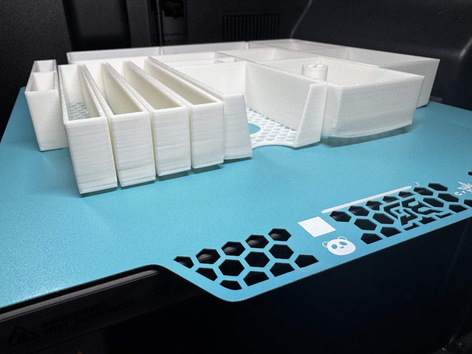 White organiser prints lifting away from the blue BIQU CryoGrip Pro Glacier plate.